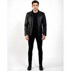 Man wearing a black leather jacket, black shirt, and black pants on a white background