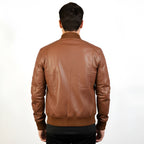 Brown leather jacket worn by a person on a white background