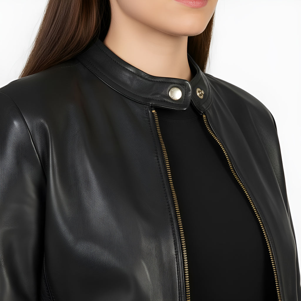 Close-up of a black leather jacket with gold zipper on a white background