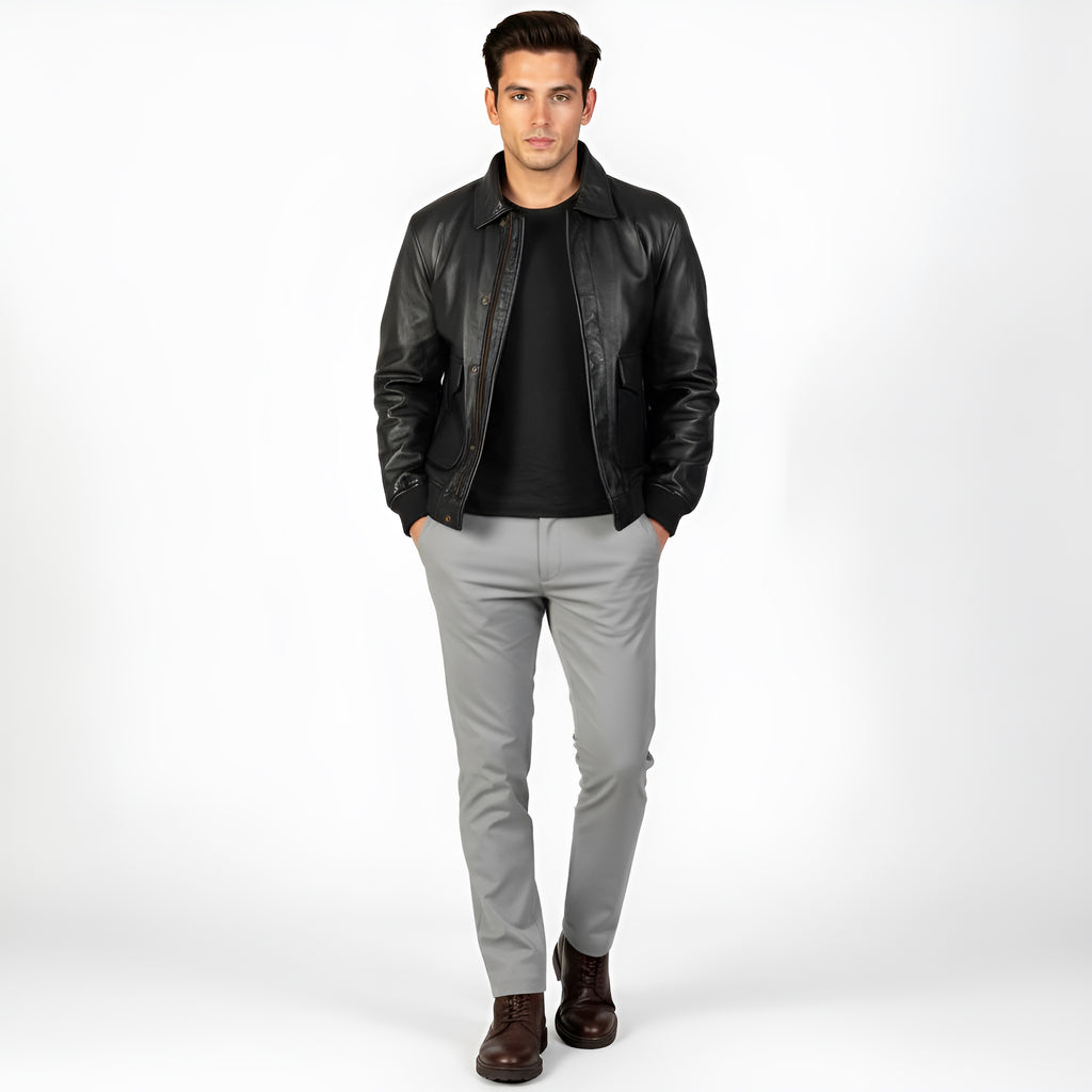 Man wearing a black leather jacket, black shirt, gray pants, and brown shoes on a white background