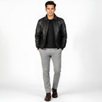 Man wearing a black leather jacket, black shirt, gray pants, and brown shoes on a white background
